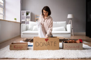Woman Donating, Decluttering And Cleaning Up Wardrobe Clothes Into Boxes