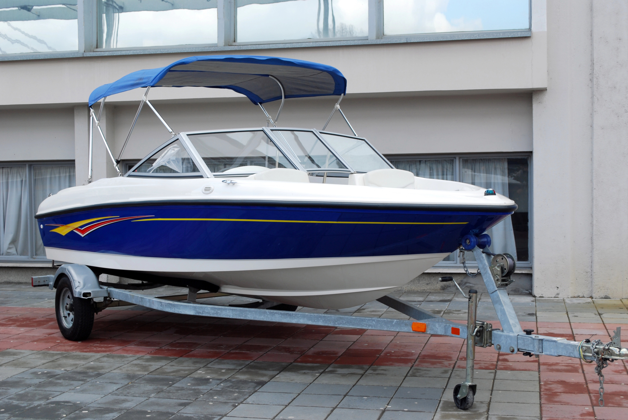Blue and white speed boat with bimini on a trailer ready to be transported to storage